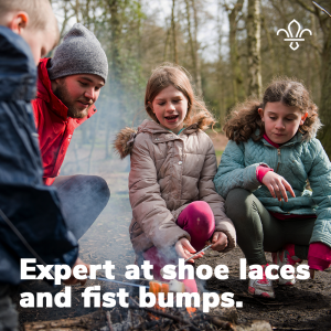 Expert at shoe laces and fist bumps. A volunteer with three Scouts.